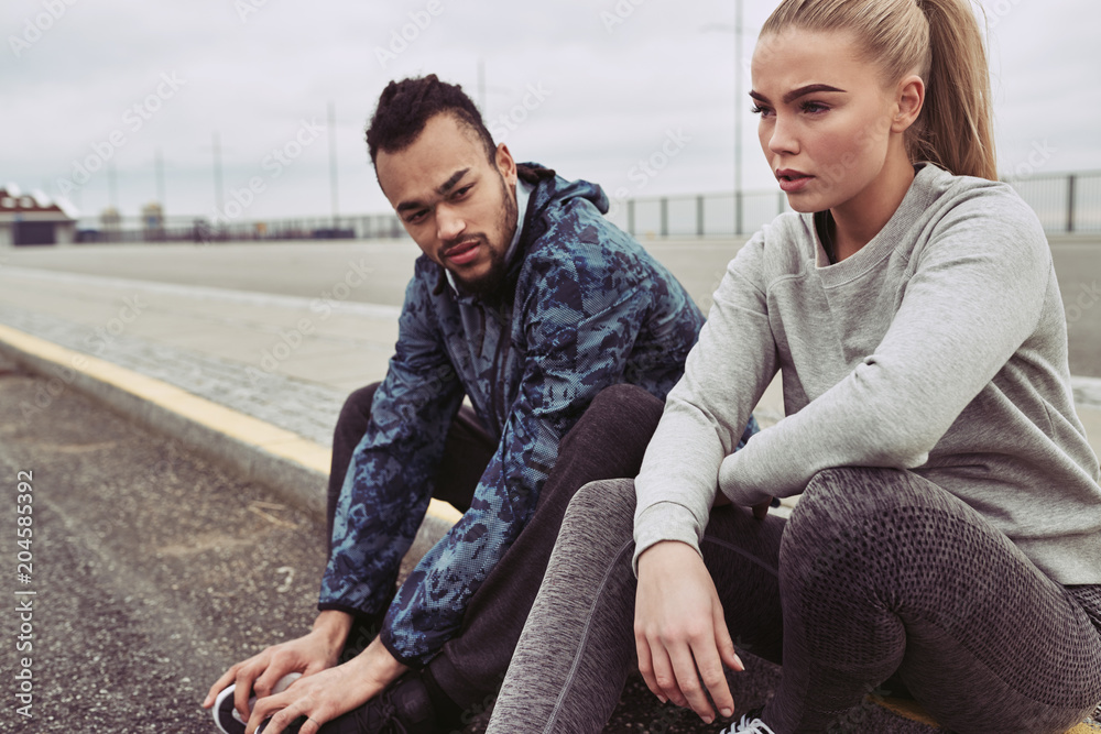 Tired couple resting on a road during an outdoor run Tired couple resting on a road during an outdoor run