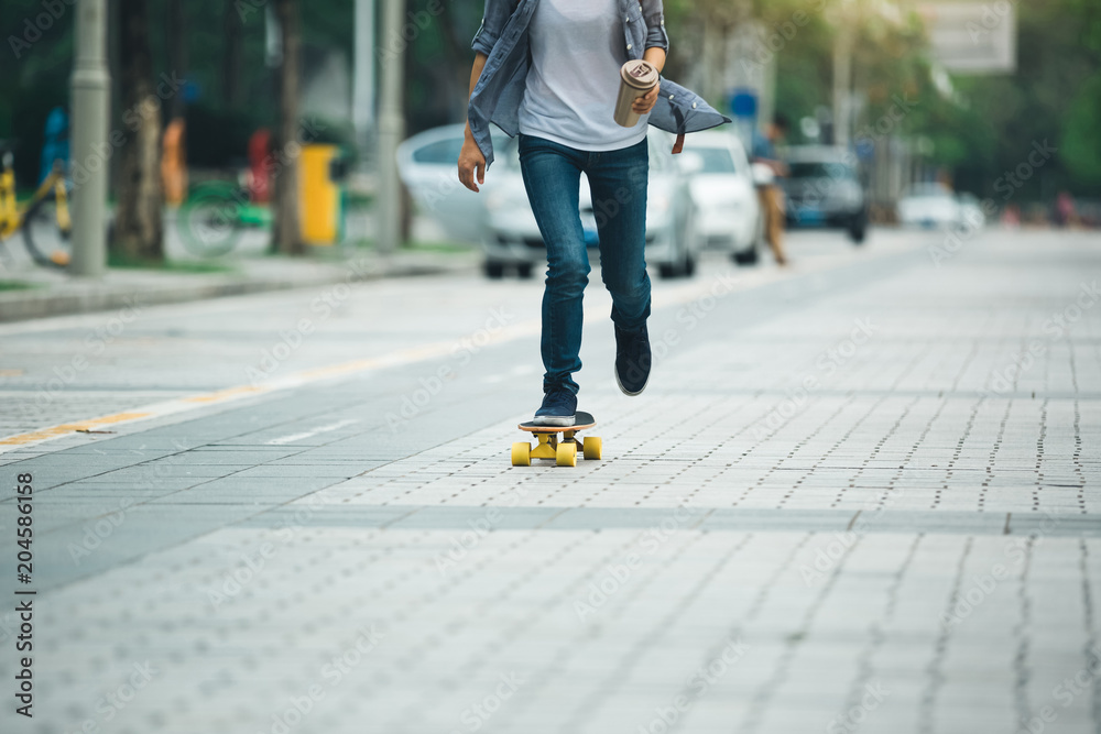 Fototapeta premium woman skateboarding with coffee cup in hand on city street