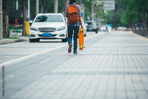 woman walking with sakteboard in hand on city street