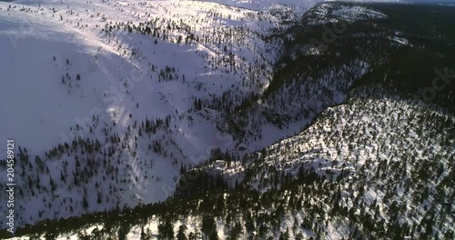 Finland Lapland, C4k aerial tilt view of Isokuru canyon between pyhatunturi and ukonhattu tunturi, Above isokuru canyon, on a cold, sunny winter day, in Pyha-luosto national park, in North Finland photo