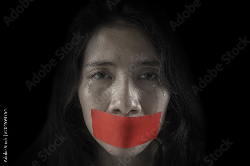 Unhappy woman with her mouth covered by tape photo