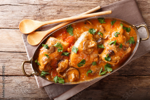 Fototapeta Tasty rustic French food: chicken with mushrooms stewed in sauce close-up