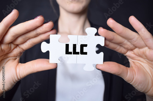 Businessman holding a puzzle with the inscription:LLC