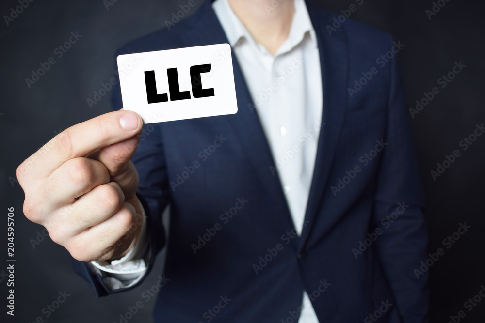 Businessman shows business card with the inscription:LLC Businessman shows business card with the inscription:LLC