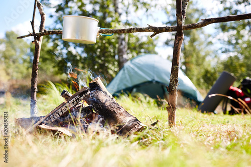 Small aluminum pan hanging on stick over campfire where food for backpackers is being cooked