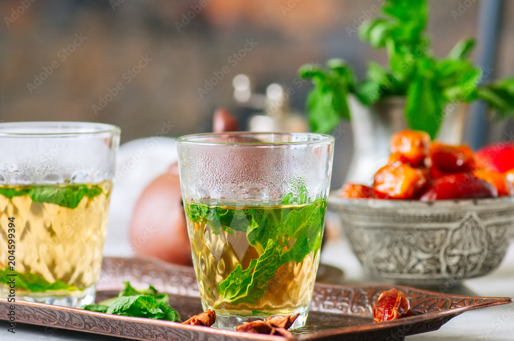 Traditional moroccan mint tea with dates on a vintage tray. White stone background. Traditional moroccan mint tea with dates on a vintage tray. White stone background.