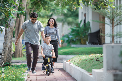 kids ride bicycle push by his father