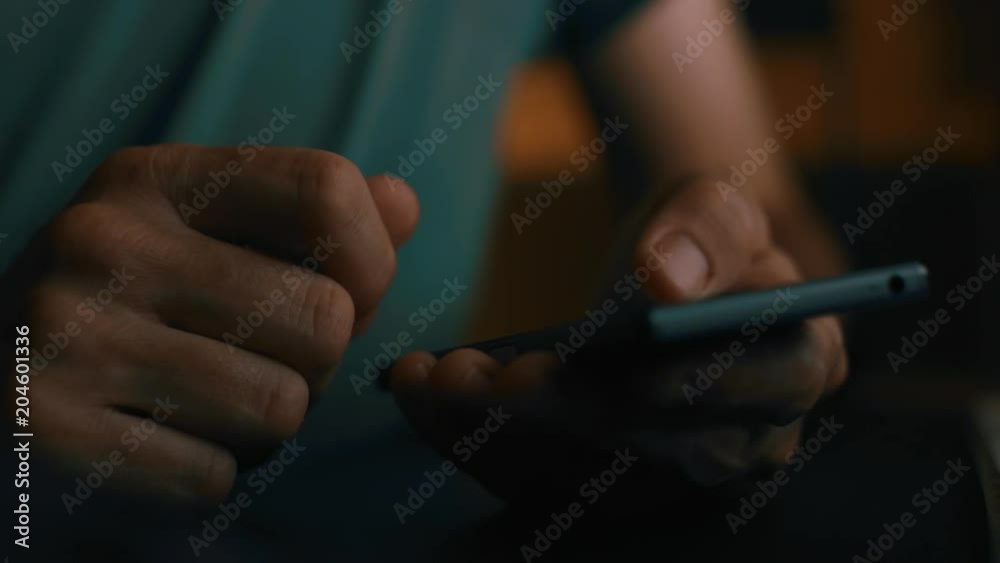 Close up of hands using smartphone in dark home office interior, low key footage Close up of hands using smartphone in dark home office interior, low key footage