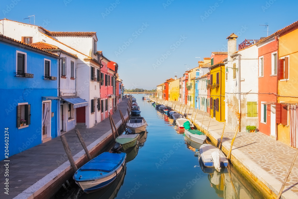 Beautiful colorful houses and a canal with boats in Burano, Venice