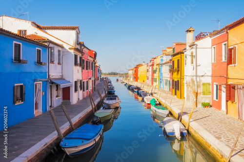 Beautiful colorful houses and a canal with boats in Burano, Venice