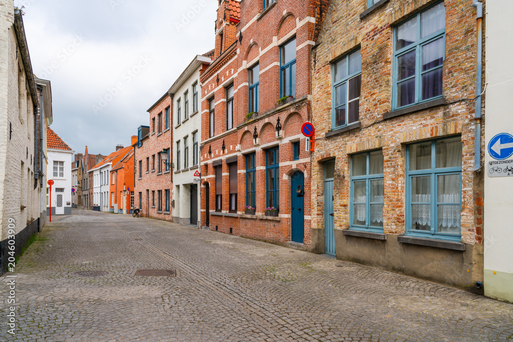 Old historical buildings along cobbled street in Bruges, Belgium