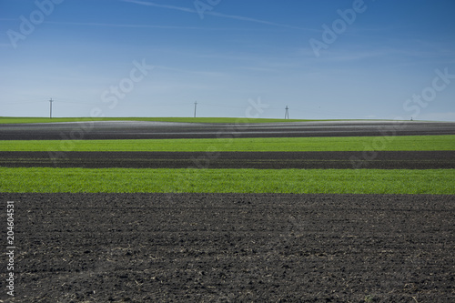 Belts of green and ploughed field, horizon and blue sky