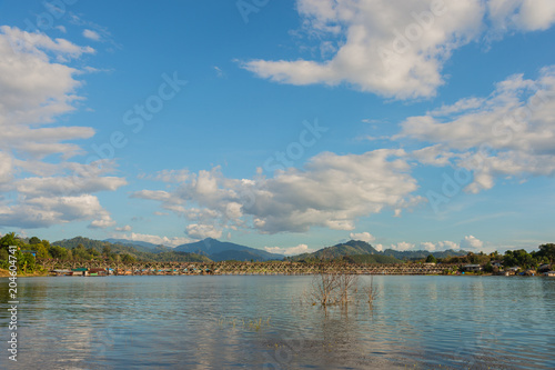 Landscape of Uttamanusorn Bridge or Mon Bridge with reflection on river and blue sky in Sangkhlaburi district,Kanchanaburi province,Thailand. photo