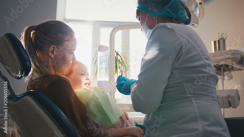 Little girl on reception at the dentist, the stomatologist cleaning and watering the child's teeth, girl smiling