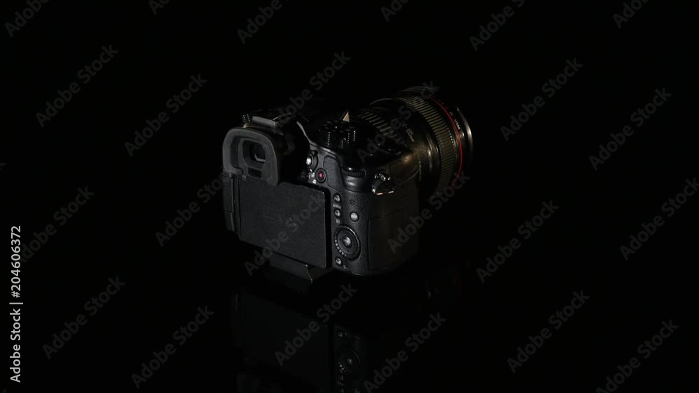 Professional digital photo camera rotate on black background