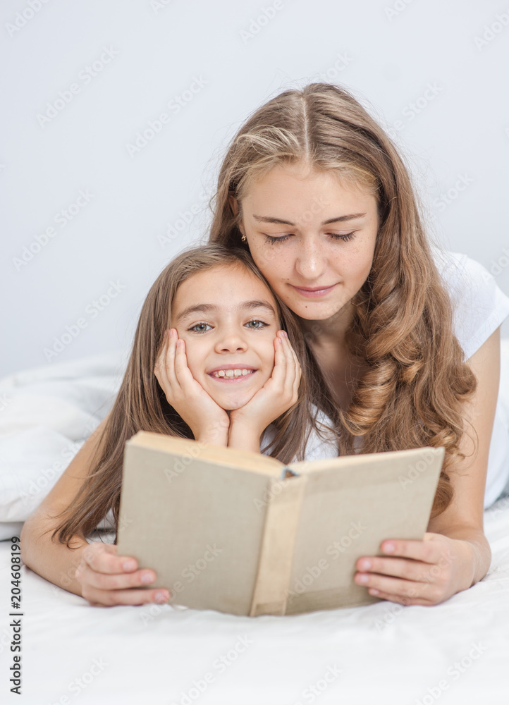 Mom and daughter reading a book together on the bed Mom and daughter reading a book together on the bed