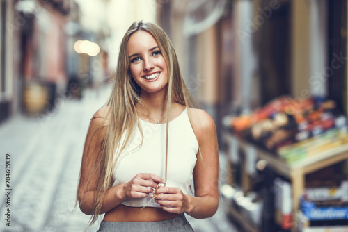 Beautiful young blonde woman smiling in urban background. photo