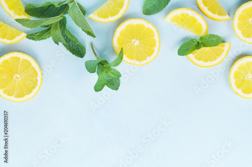 Juicy lemon slices and mint leaves on blue table top view. Flat lay style.