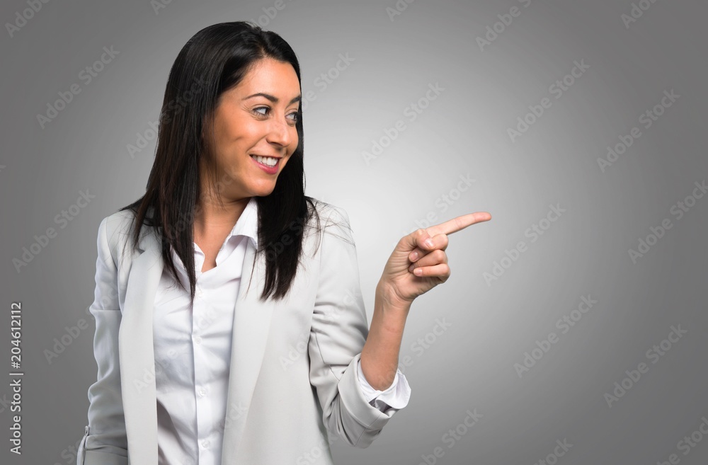 Pretty woman pointing to the lateral on grey background Pretty woman pointing to the lateral on grey background