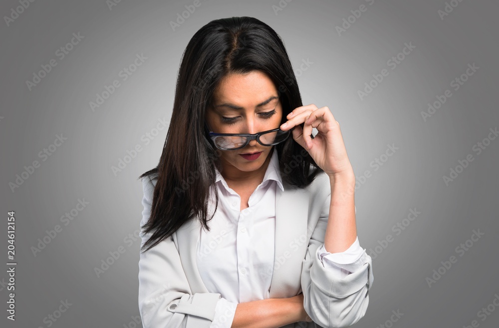 Pretty woman with glasses looking down on grey background Pretty woman with glasses looking down on grey background