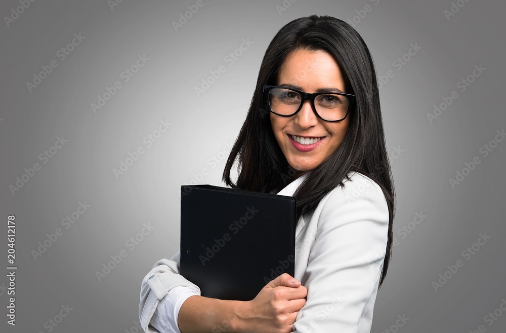 Pretty woman with glasses and holding binder on grey background