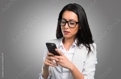 Pretty woman talking to mobile on grey background