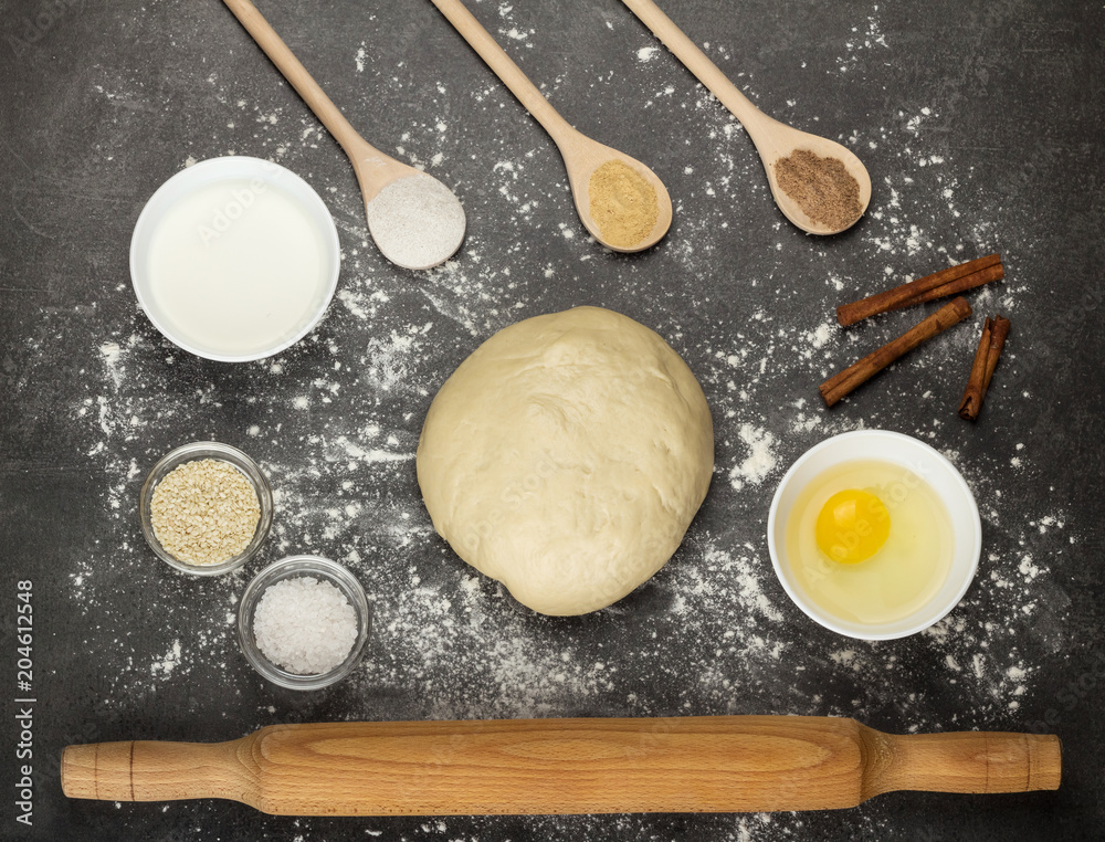 Ready-made dough lump, rolling pin, spoons with spices, on gray surface Ready-made dough lump, rolling pin, spoons with spices, on gray surface