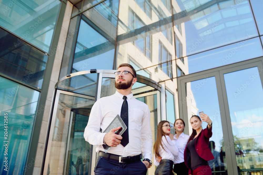 custom made wallpaper toronto digitalA young male manager with a tablet in his hands against the background of the girls. Office staff in the background of a multi-storey glass building. Lifestyle. Businessman