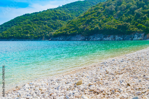 Fototapeta Naklejka Na Ścianę i Meble -  Crystal clear turquoise sea waters of a pebble beach. Poros beach in Lefkada ionian island in Greece