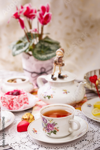 Porcelain cup of tea with lemon and sweets
