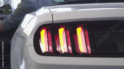 Close up shot of car lights flashing as a male driver getting into the car at the dealership showroom. Mosern cars for sale. Automobile rental service. Technology, automotive industry concept. photo