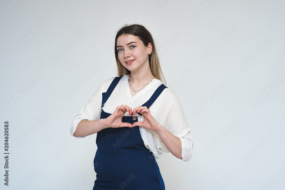 Portrait of a beautiful girl on a white background showing a heart with her hands