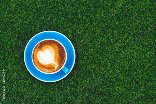 Hot coffee, cappuccino in a cup of blue coffee placed on grass