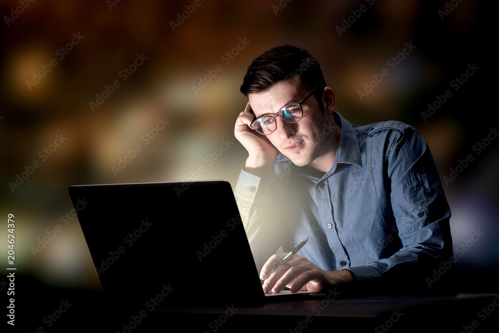 Young handsome businessman working late at night in the office Young handsome businessman working late at night in the office