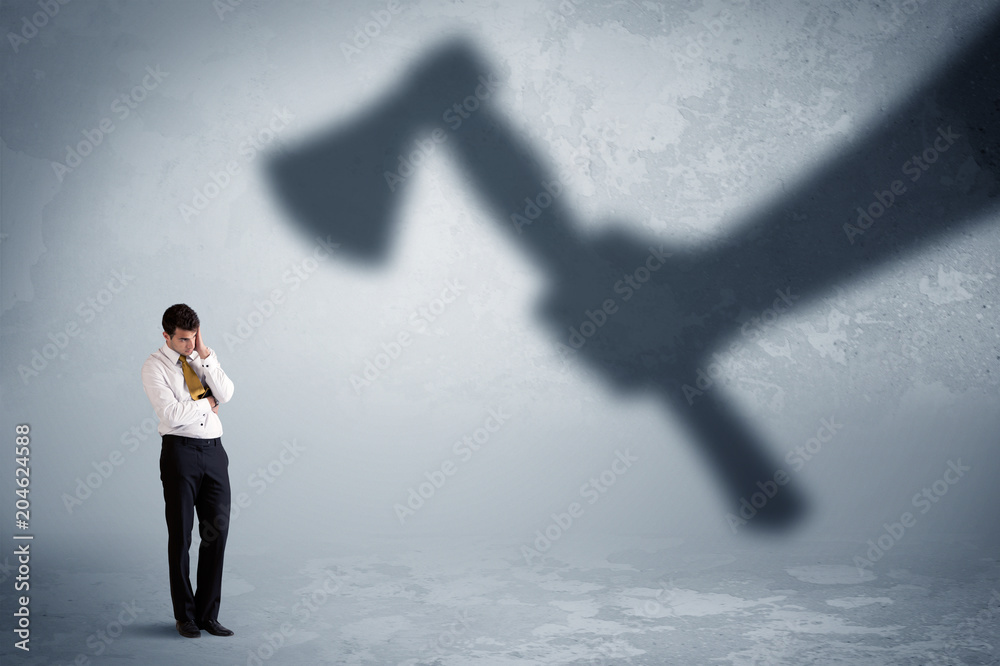 Obraz premium Businessman afraid of a huge shadow hand holding an axe concept on background