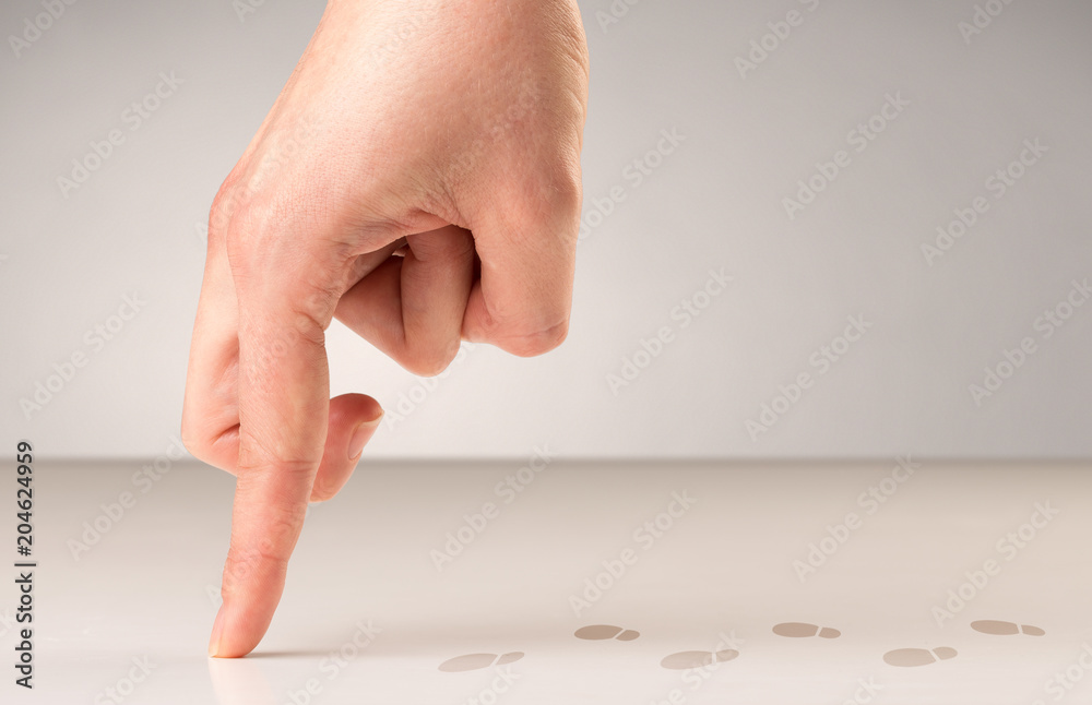 Female fingers walking on white surface with footsteps behind it Female fingers walking on white surface with footsteps behind it