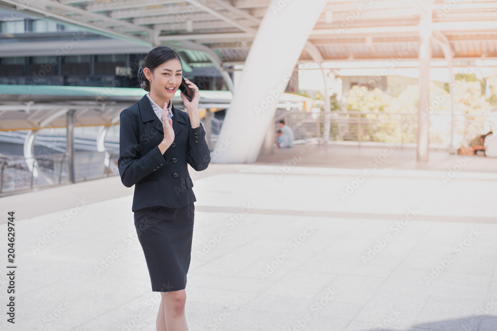 Asian business woman smile and hold cell phone to talk about business success, and copy space for text Asian business woman smile and hold cell phone to talk about business success, and copy space for text