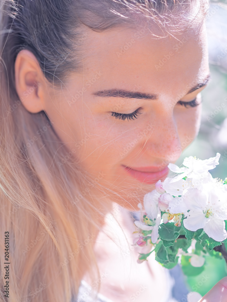 Naklejka premium Portrait of the young girl at the white spring flowers blossom