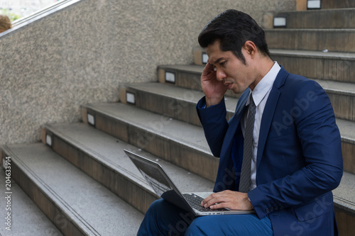 Papier peint A businessman sit on the stairs and his hands clasped head,the feeling of stressed, sadness or displeasure caused by the non fulfillment of one's hopes or expectations