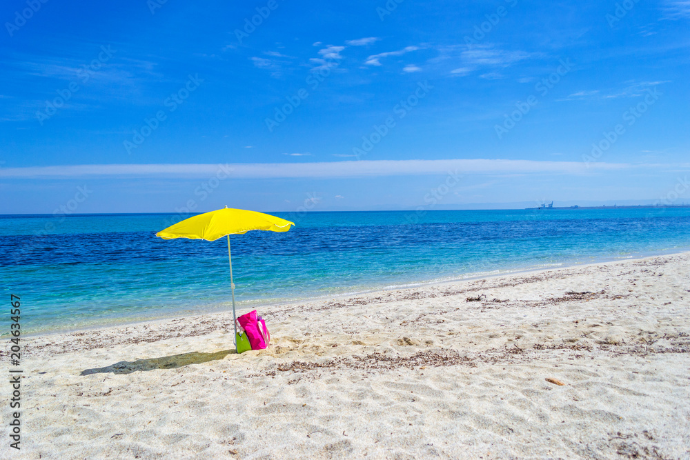 Yellow parasol on a white sand beach in Sardinia