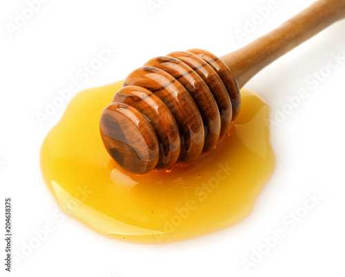 Wooden honey dipper in honey puddle