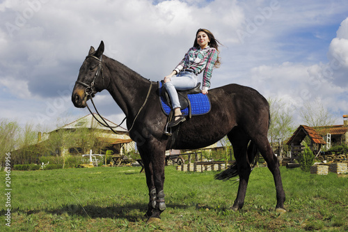 the girl is walking in nature on horseback on a black horse © stalk