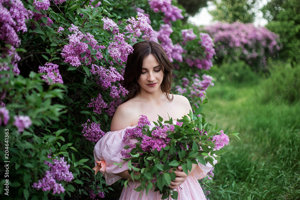 beautiful girl in a smart dress on a background of blossoming lilac close-up holding a bouquet of lilac in hands beautiful girl in a smart dress on a background of blossoming lilac close-up holding a bouquet of lilac in hands