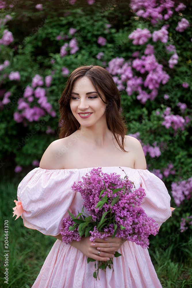 beautiful girl in a smart dress on a background of blossoming lilac close-up beautiful girl in a smart dress on a background of blossoming lilac close-up