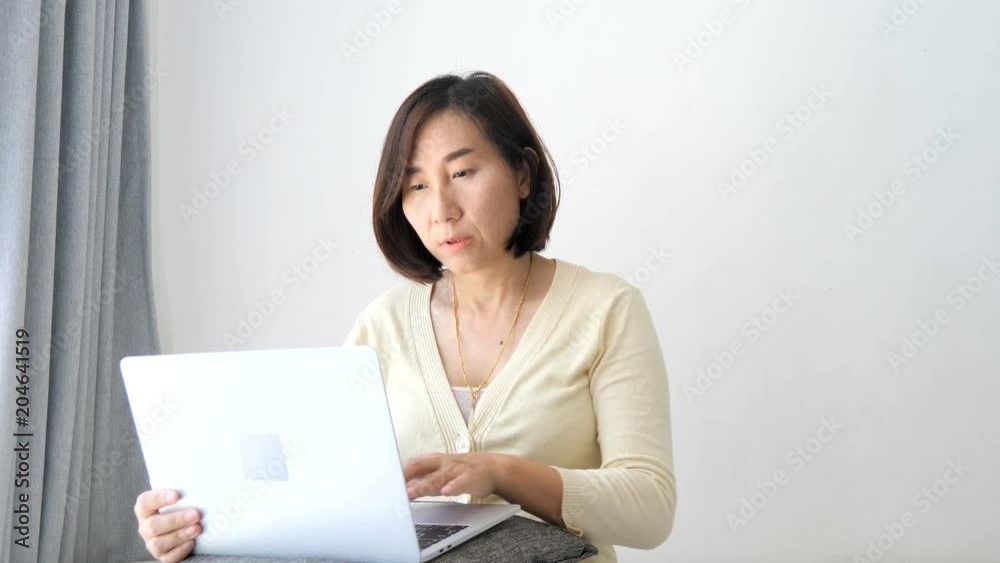 Asian woman relaxing on sofa using laptop near window at home. Asian woman relaxing on sofa using laptop near window at home.