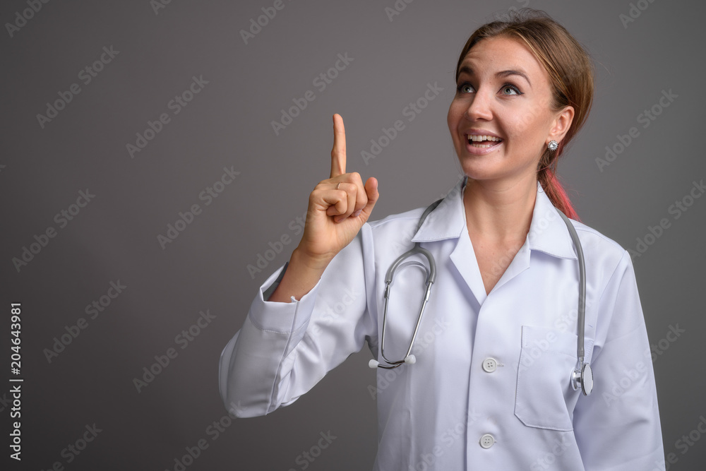 Young beautiful woman doctor against gray background