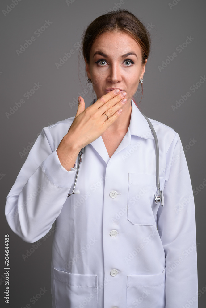 Young beautiful woman doctor against gray background Young beautiful woman doctor against gray background
