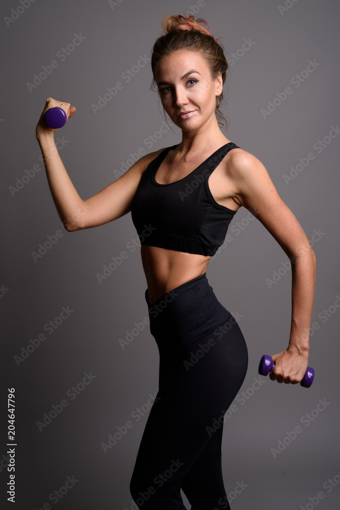 Young beautiful woman ready for gym against gray background Young beautiful woman ready for gym against gray background