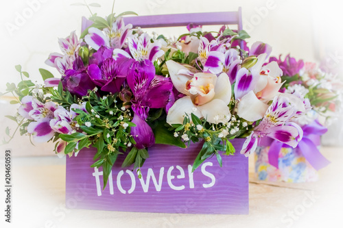 Florist at work: pretty young blond woman making fashion modern bouquet of different flowers