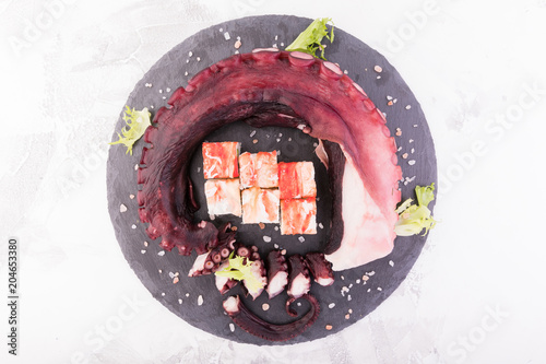 Beautiful octopus tentacle on the dark plate with rolls